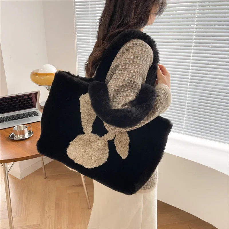 Soft plush tote bag with cartoon rabbit ears on the front in a solid colour.