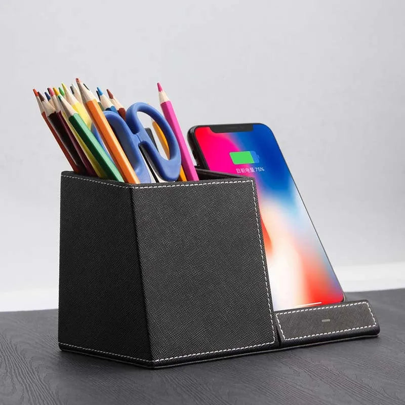 Black leather wireless charging station with built-in pen holder on a wooden desk.