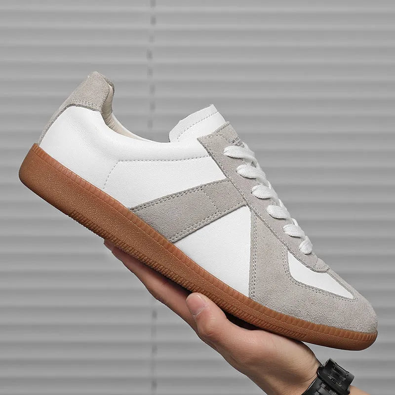 White low-top retro unisex sneakers with round toe and lace-up front on a plain background.