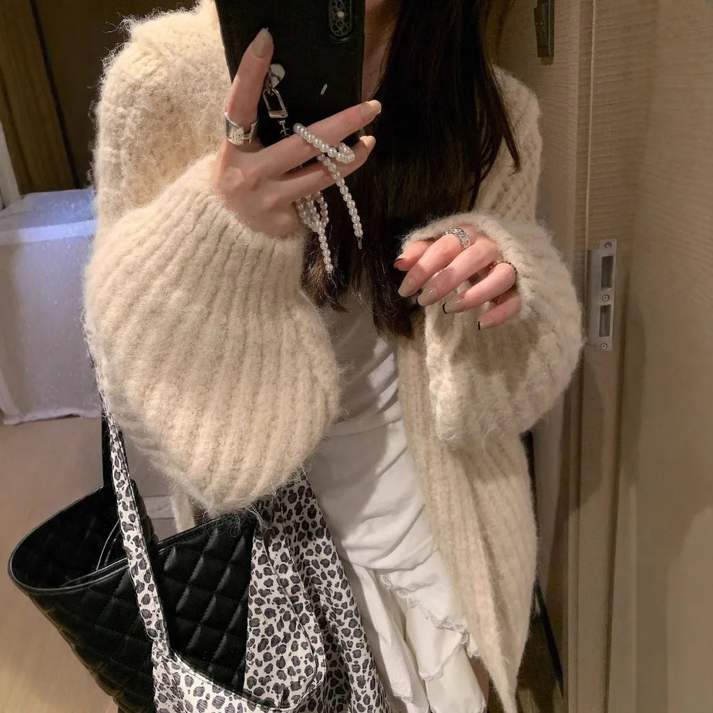 A woman wearing a thick, loose-fit hooded cardigan sweater in a milky white colour.