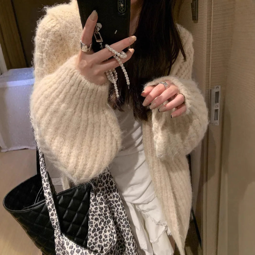 A woman wearing a thick, loose-fit hooded cardigan sweater in a milky white colour.