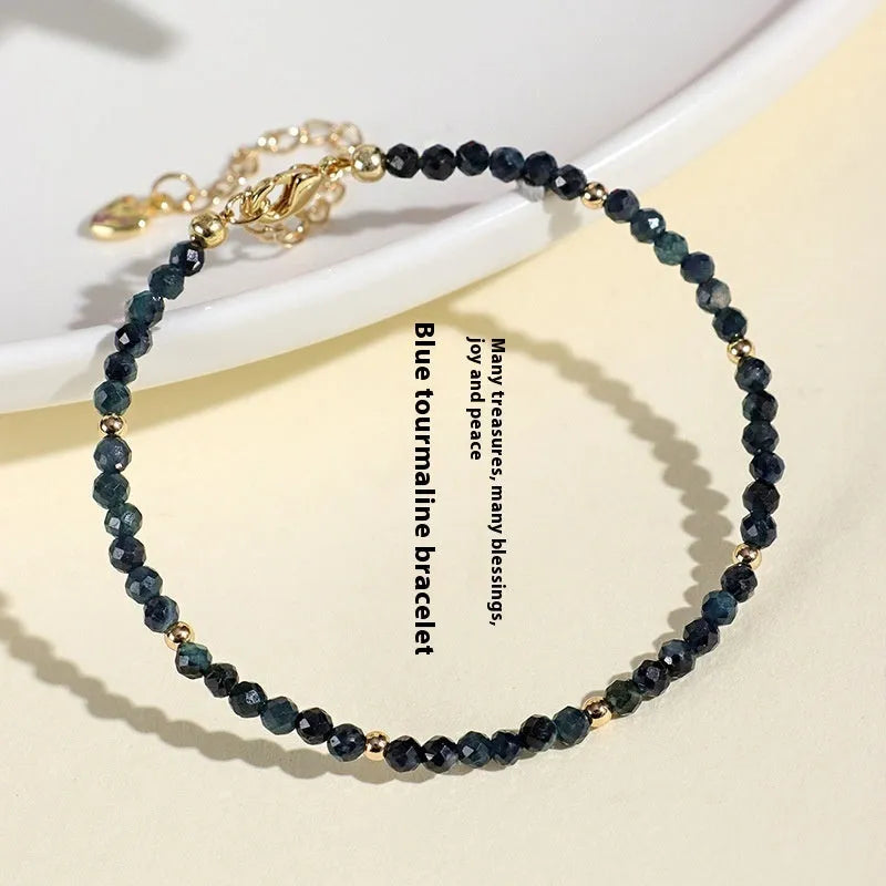 3mm blue tourmaline cut bead bracelet with gold spacer beads on wrist