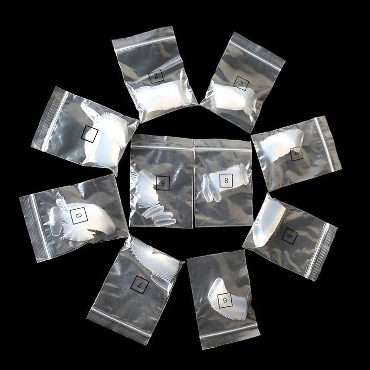 500 clear natural ABS fake nails in various sizes arranged with nail tools