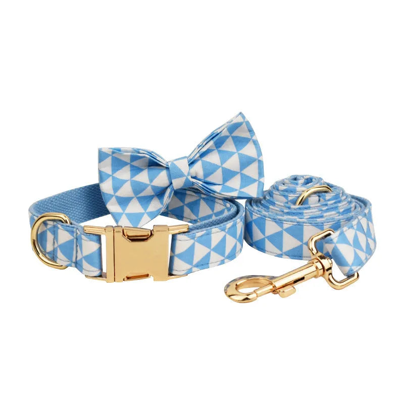 Blue cloth dog vest, matching collar with triangular ring, rope leash, and decorative bow laid out as a four-piece set.
