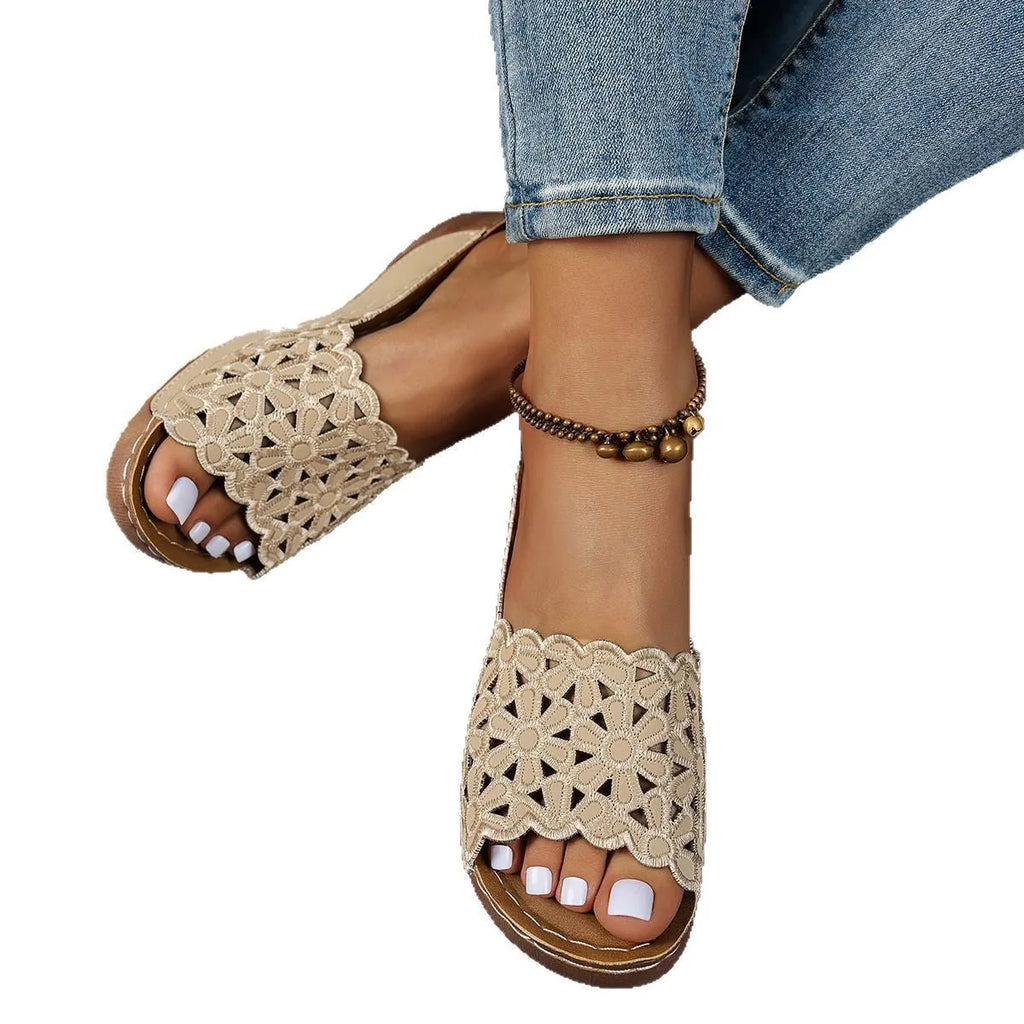 Women's black wedge beach slippers with flower cutout design on the PVC upper and a rubber sole.