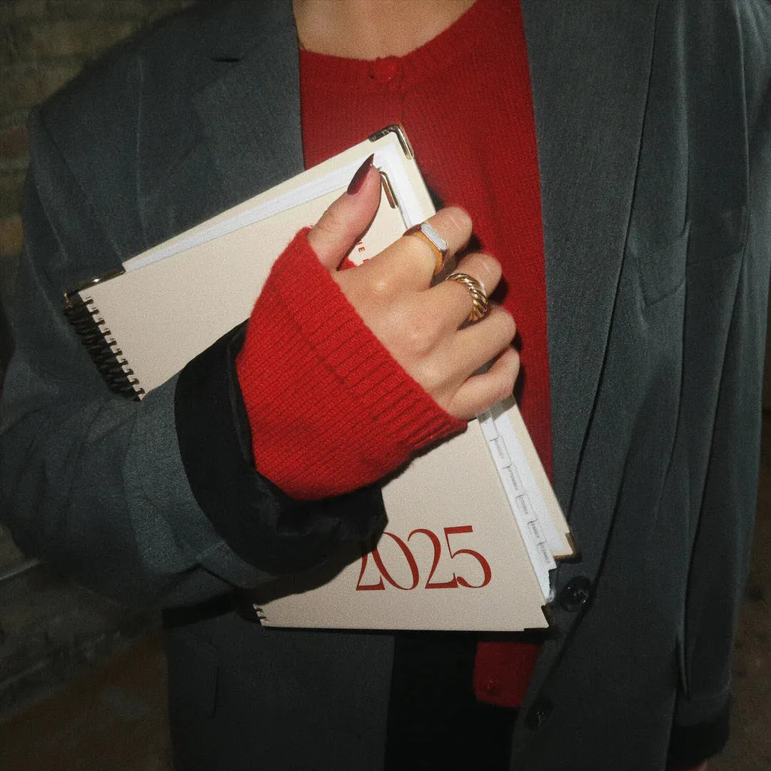 Cherry red coil-bound daily schedule notebook with wire-o binding lying open on surface