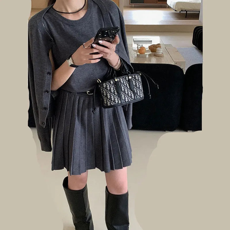 Women's grey knitted cardigan and pleated vest skirt two-piece set with a belt.