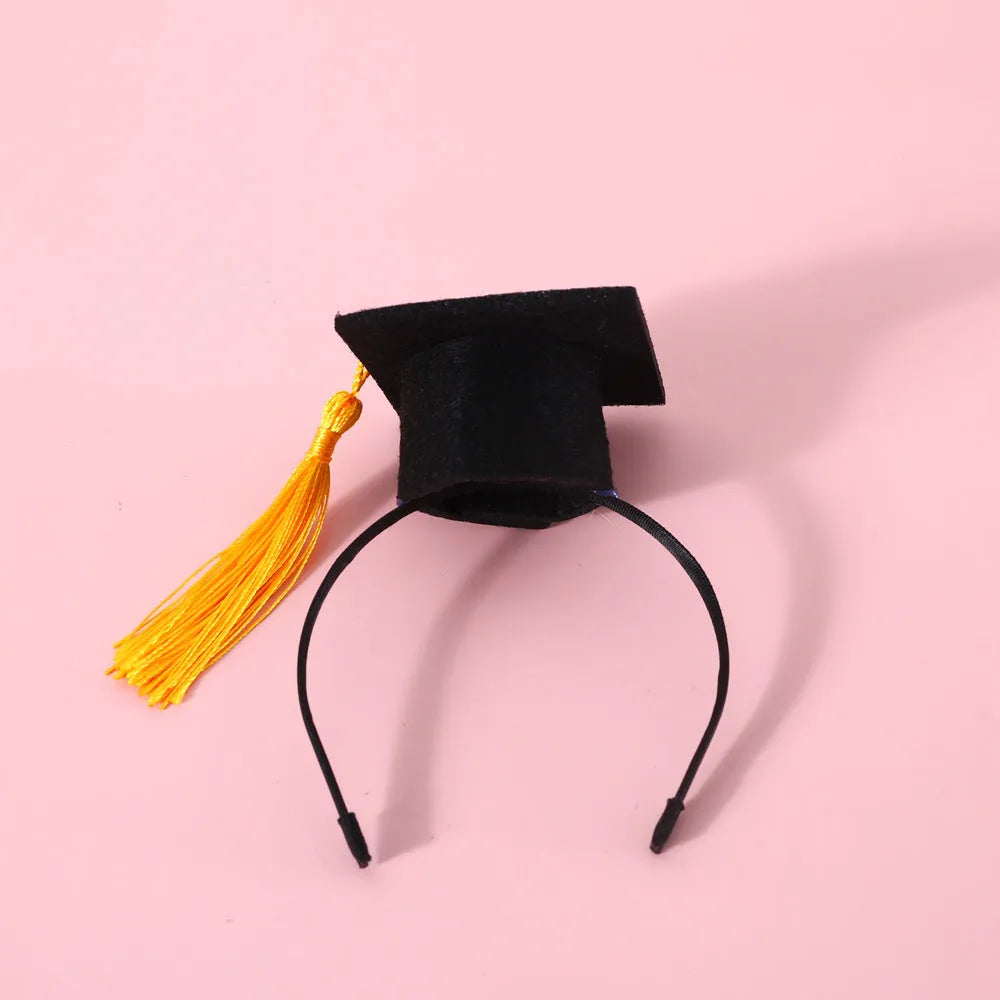 Small pet wearing a British style doctor's degree costume with an elastic hair band and a black plaid bow tie.