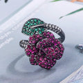 A black gold geometric flower ring with simulated red corundum stones on a model's hand.