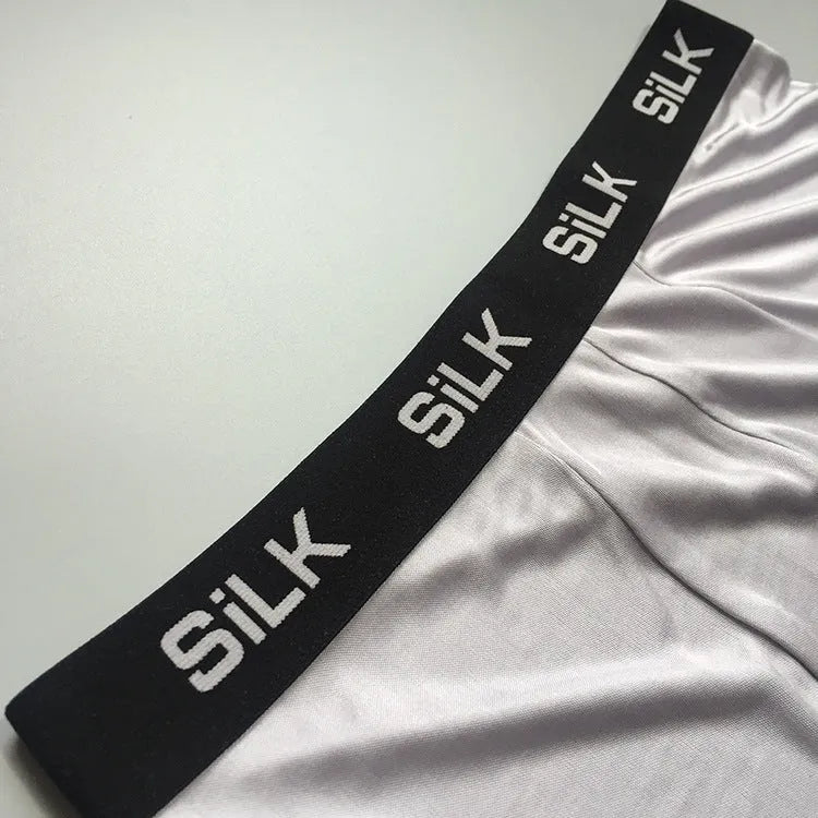 Men's loose-fitting silk shorts in navy blue, shown laid flat to display mid-waist design.