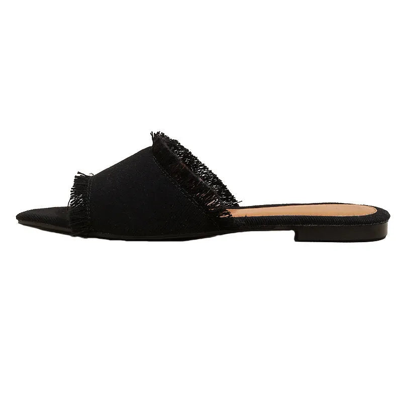 Women's denim flat slippers with tassel decoration in apricot colour on a white background.
