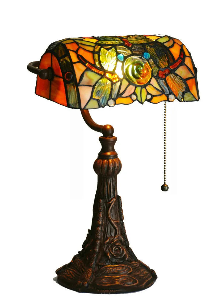 Tiffany table lamp with coloured stained glass shade and resin base on wooden desk