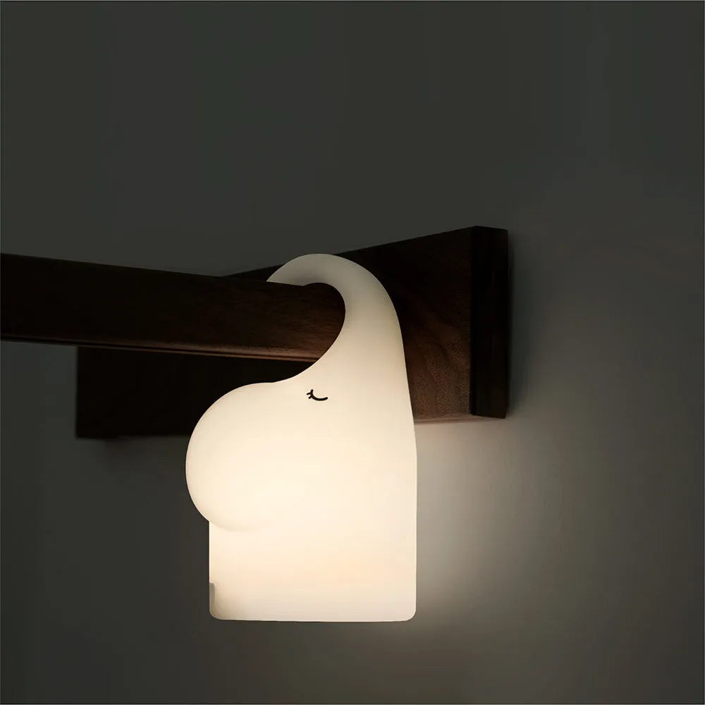 DOMI Elephant-shaped silicone night light with warm white LED glow on a bedside table.