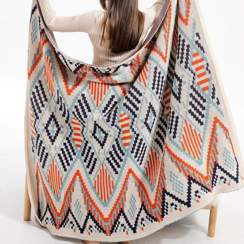 Bohemian style acrylic sofa blanket with tassel fringe in a geometric blue and pink pattern.