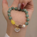 Green jade bracelet for women with a metal shell clasp on a wrist.