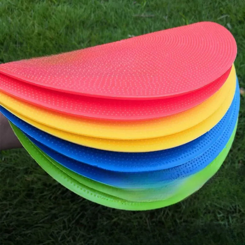 Yellow TPE football training marker disc lying flat on grass, 23cm diameter.