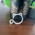 Small plastic plant clip shaped like a cat, shown in red, yellow, green, and white colours, for securing plant stems.