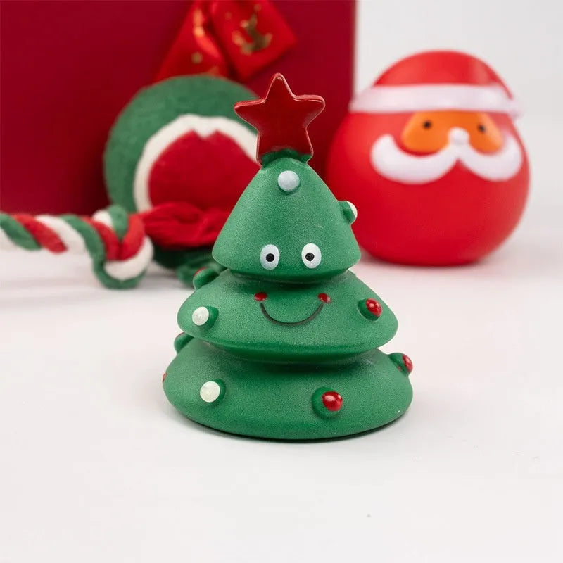 A set of red, green, and white vinyl Christmas dog toys including a Santa head, bite rope, and tennis ball.