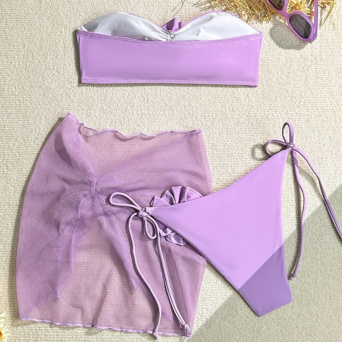 Women's pink tube top swimsuit with a large 3D flower, matching bottoms, and a skirt laid flat.