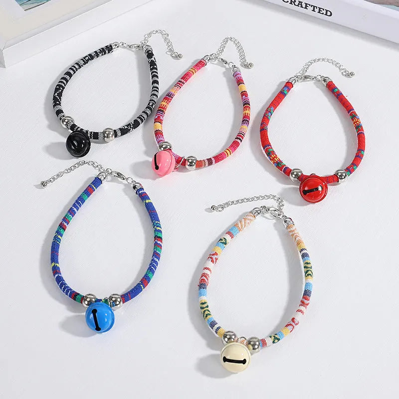 Coloured adjustable nylon pet collar with ethnic pattern, plastic quick-release buckle, and small bell.