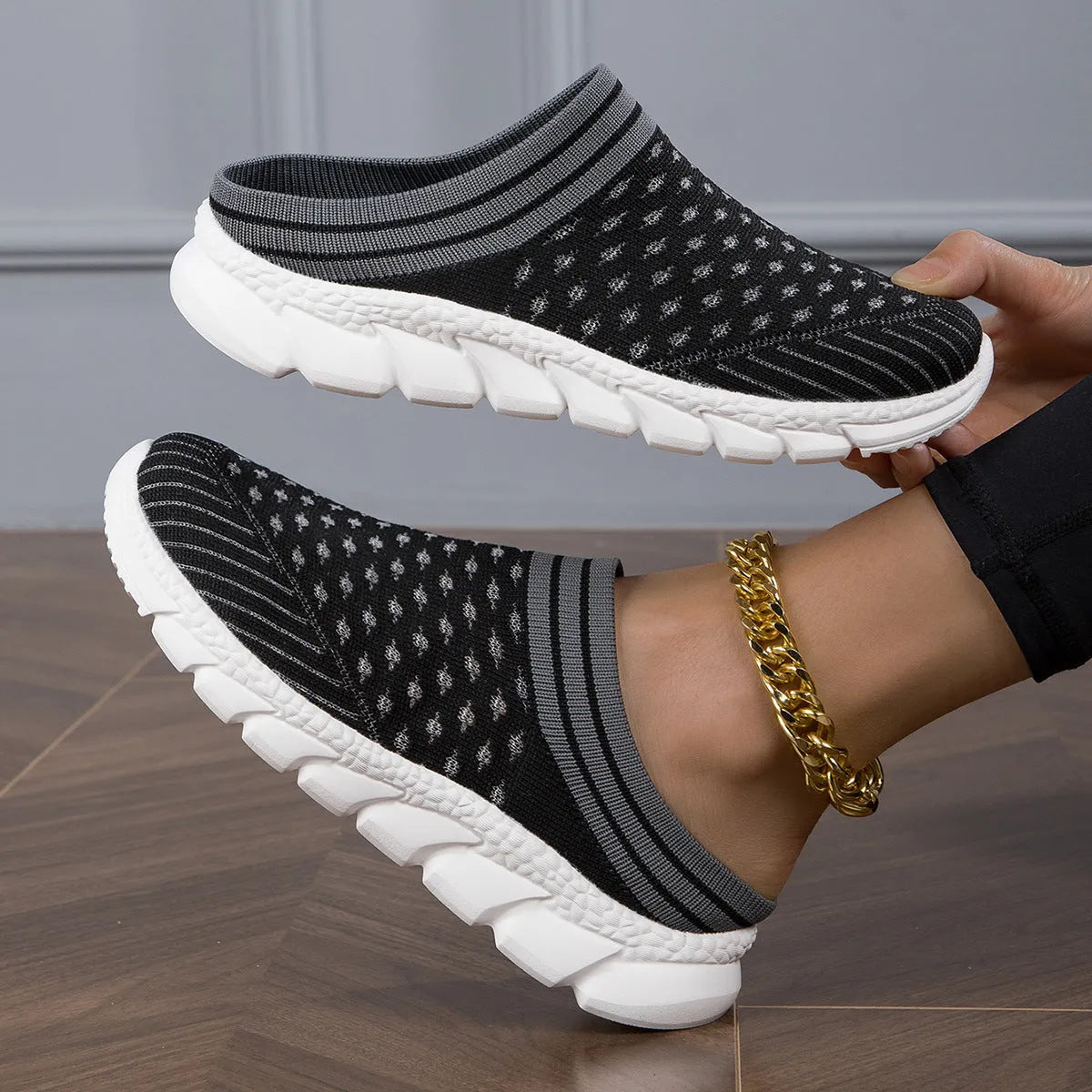 Women's black Flyknit slipper sock with striped pattern and hollowed-out design on a solid background.