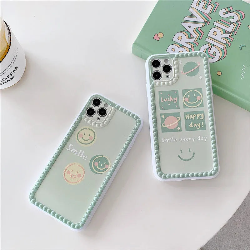 Green iPhone case with geometric smiley face pattern and polka dot border on a table.