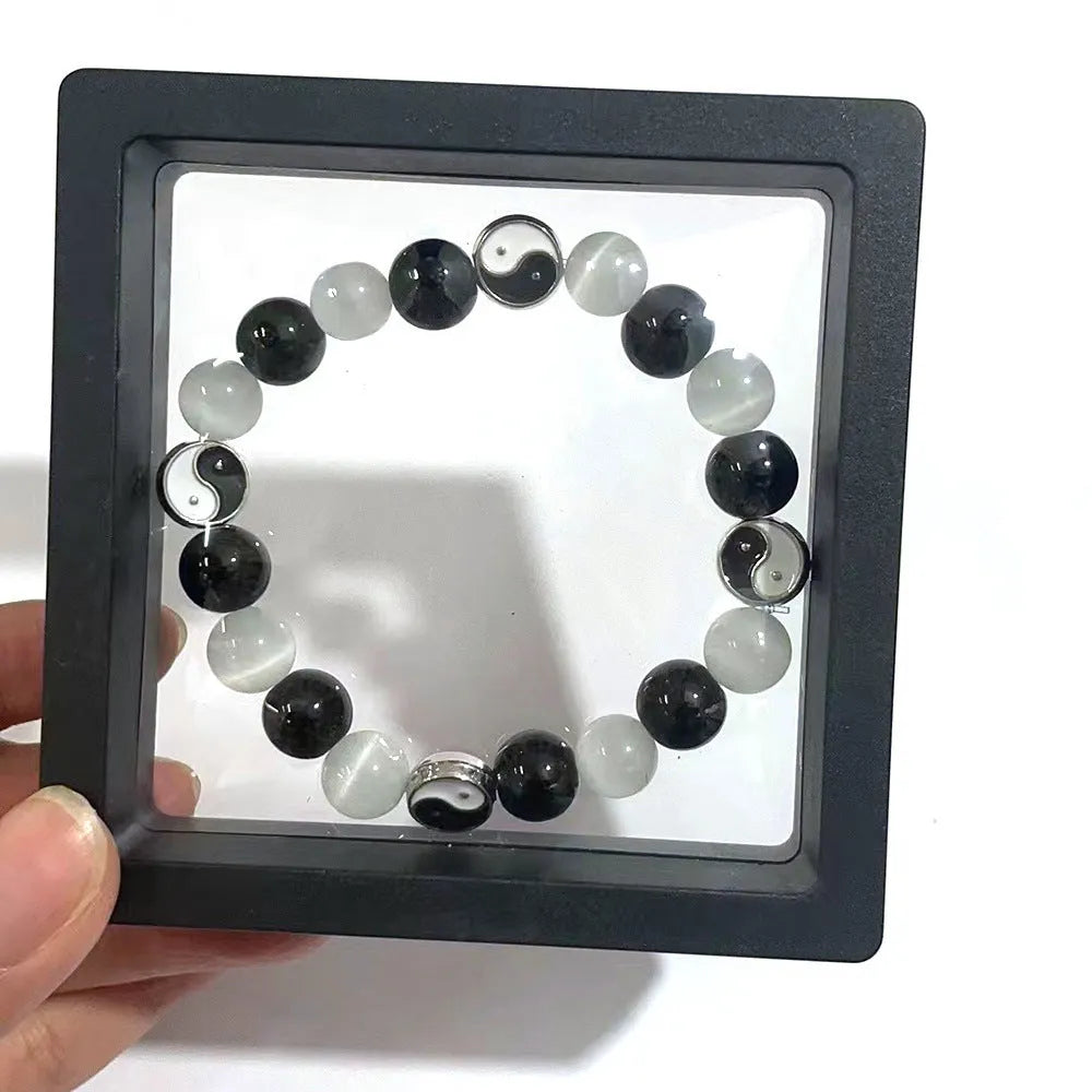 Close-up of a polished opal Tai Chi beaded bracelet with black agate ornamentation on a wrist.