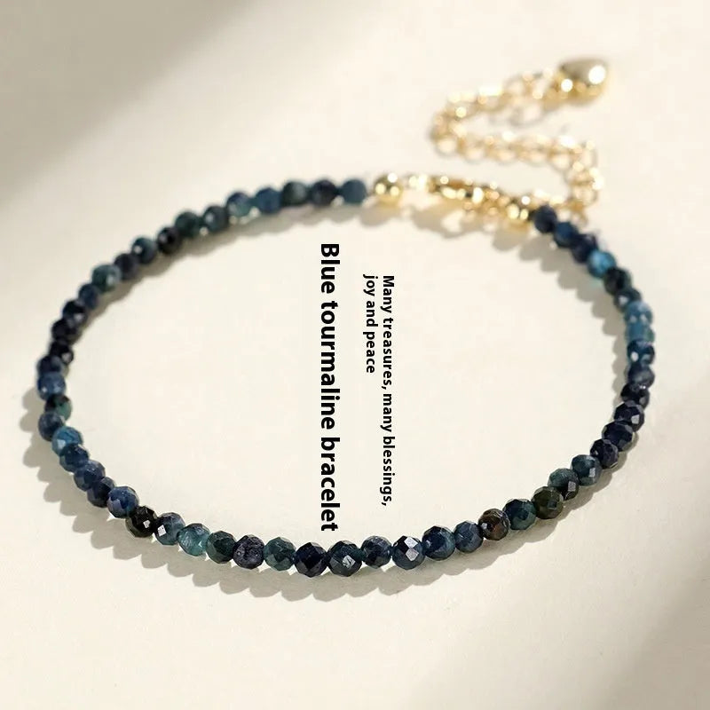3mm blue tourmaline cut bead bracelet with gold spacer beads on wrist