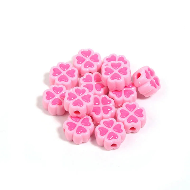 Assortment of frosted acrylic love clover beads in mixed colours on a white background.