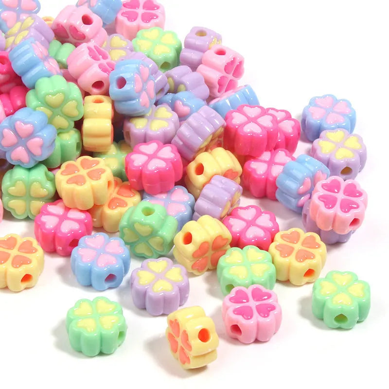 Assortment of frosted acrylic love clover beads in mixed colours on a white background.
