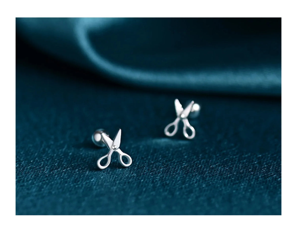 A pair of pure silver earrings with a mini scissors screws decorative design.