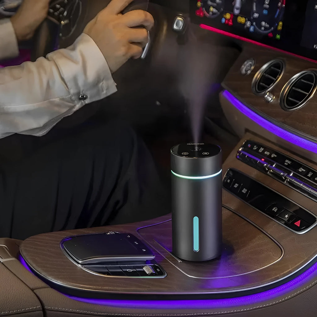 Compact black aluminium car humidifier and essential oil diffuser with USB cable on a desk.