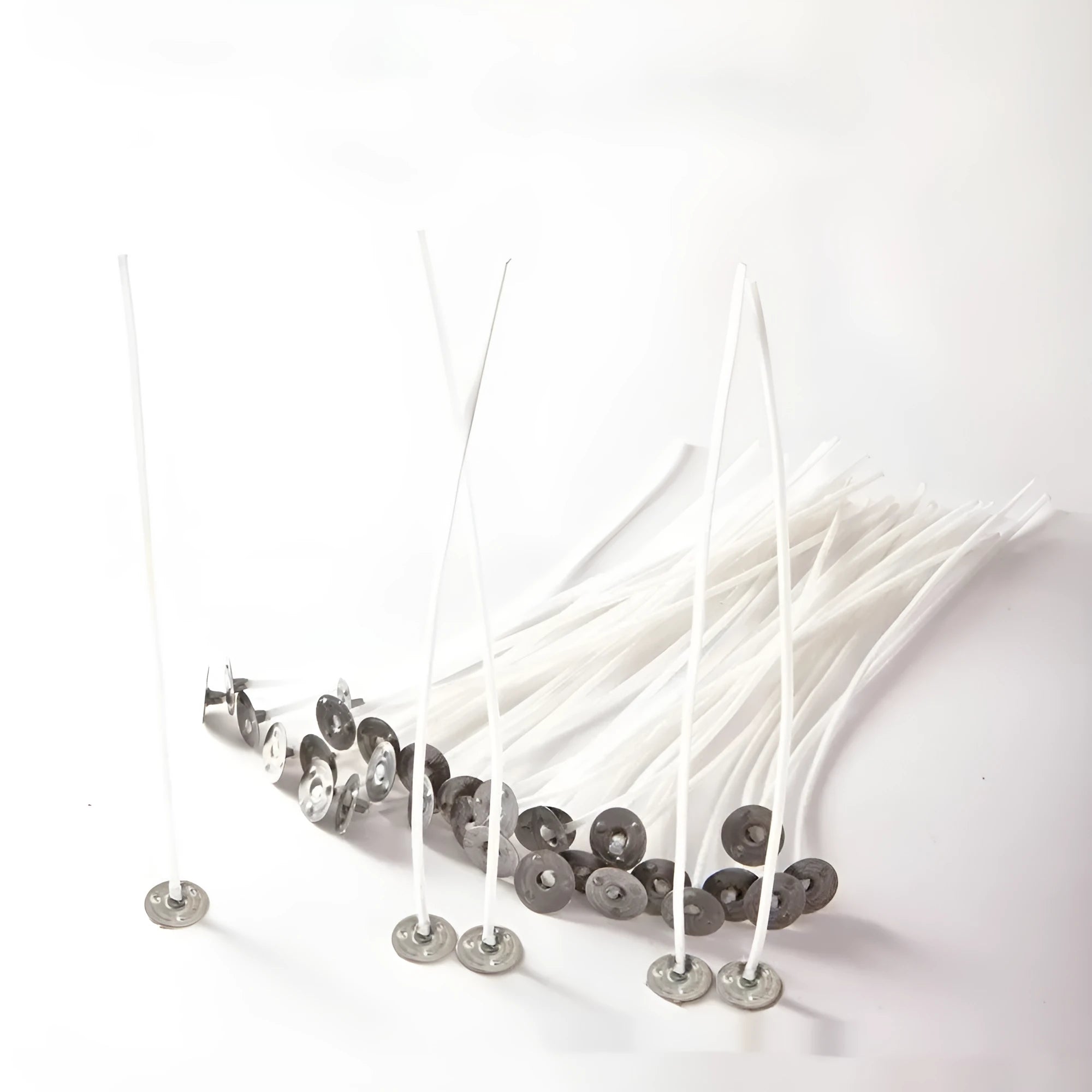 White cotton candle wicks in three lengths: 2.6cm, 6cm, and 8cm, laid out on a surface.