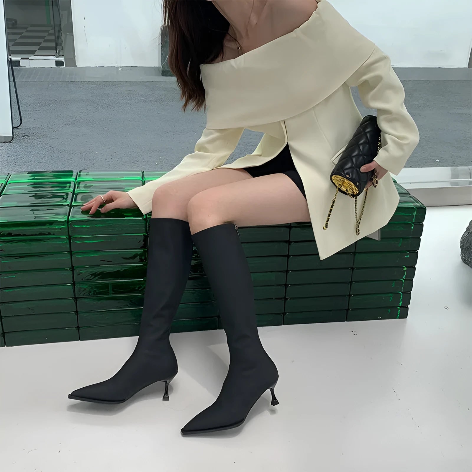 Women's black pointed toe below knee boots with back zipper and stiletto heel on grey background