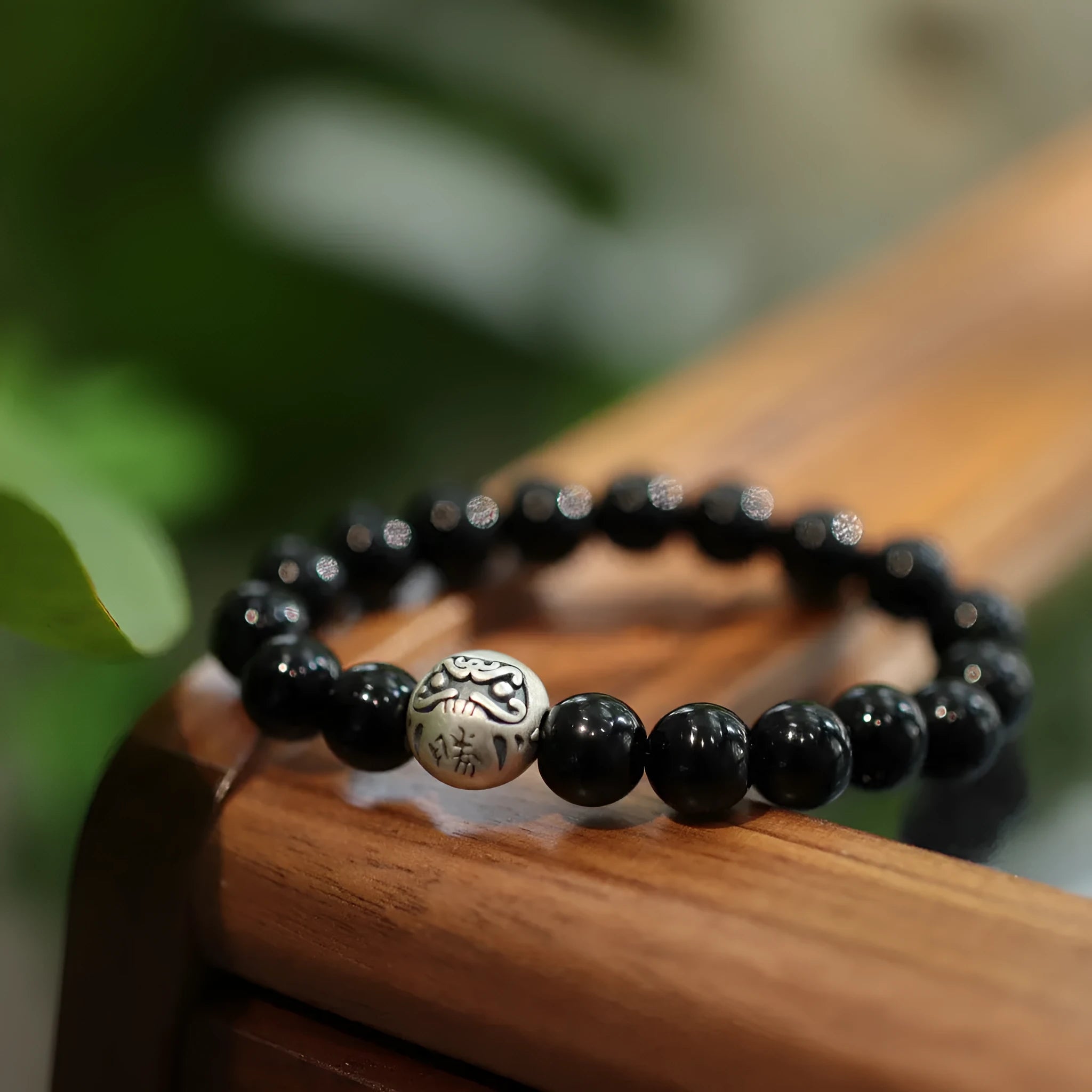 Handmade women's black agate bracelet with 10mm beads and a sterling silver clasp on a wrist.