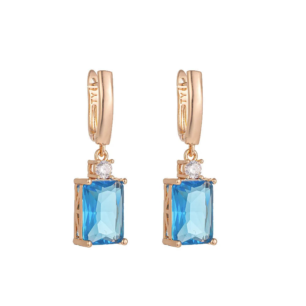 A pair of square-shaped gold-coloured earrings with a geometric design on a white background.