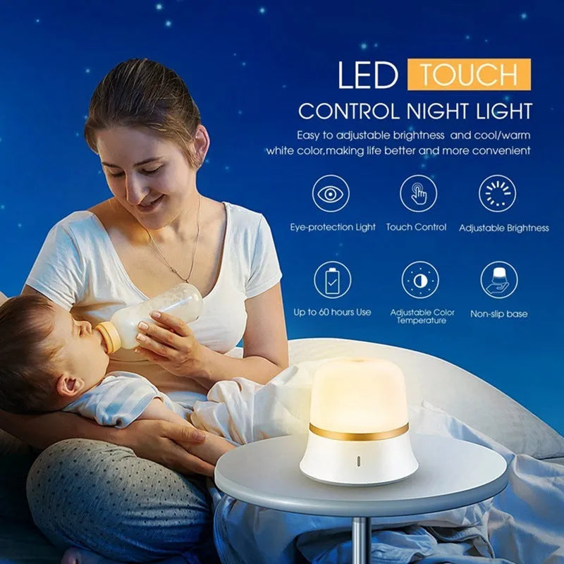 White baby night lamp with touch controls for dimming and colour change on a bedside table.