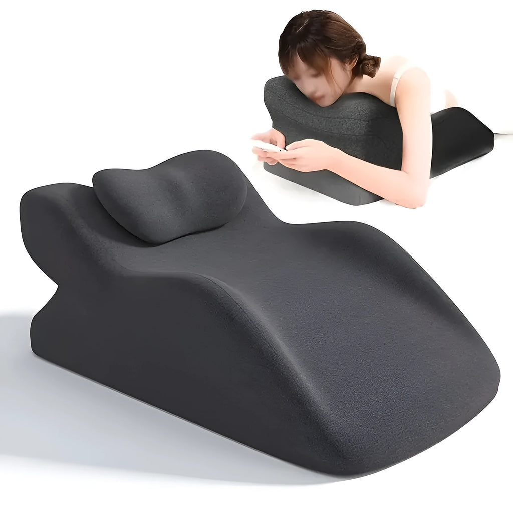 A flat stomach sleeper pillow shown on a bed, designed for prone sleeping and reading.