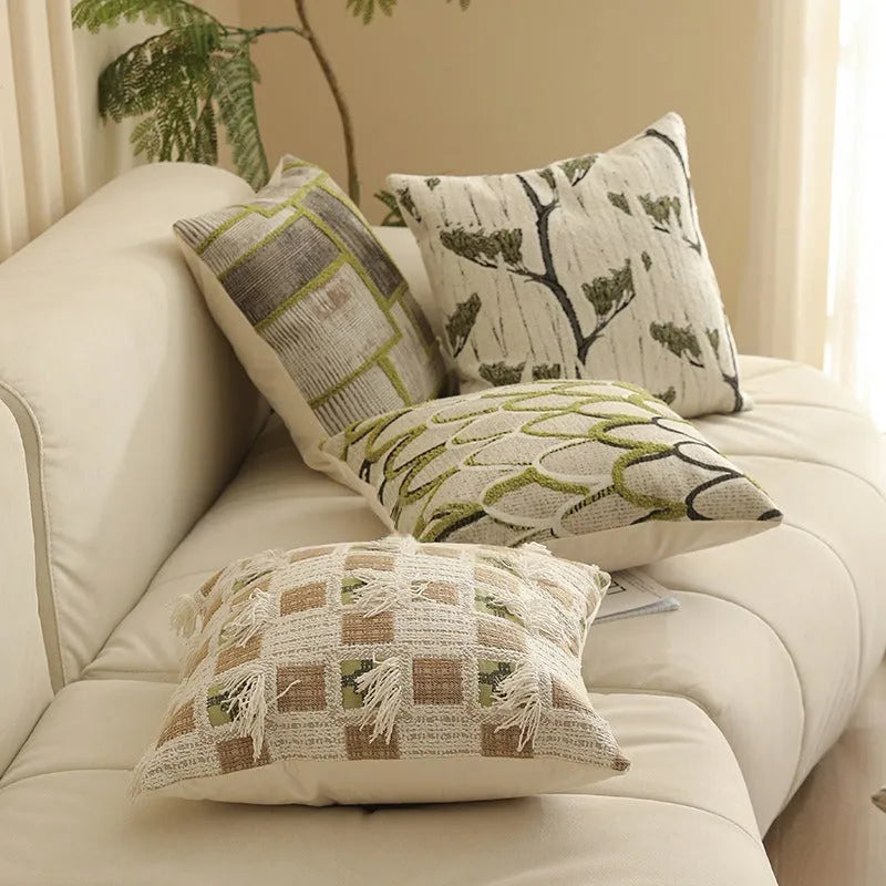 Square jacquard pillow cover with botanical pattern on a sofa, showing one of eight available colour options.