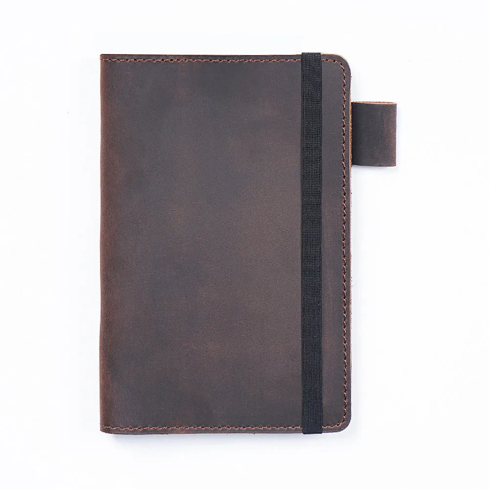 Handmade notebook with cowhide cover open on a table, showing 100 gsm wood-free paper inside