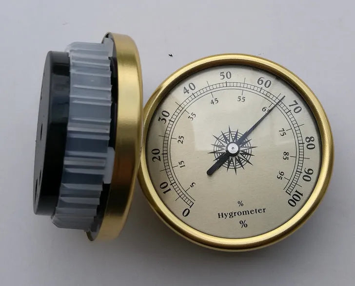 Silver analog hygrometer and thermometer with aluminium ring and dial showing temperature and humidity scales