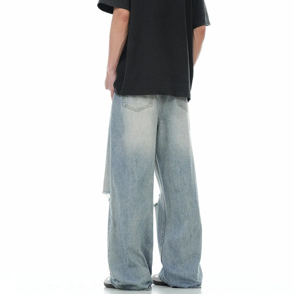 Man wearing blue retro-style straight-leg jeans with a ripped, distressed finish on the legs.