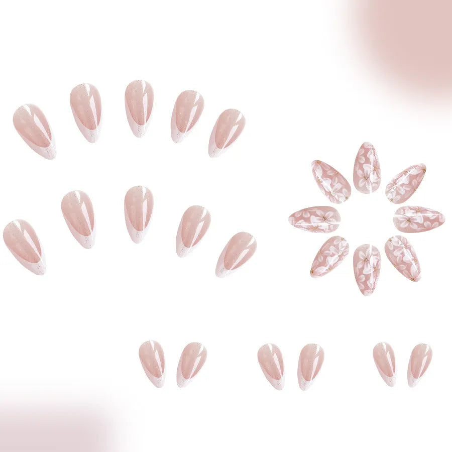 Short glossy almond-shaped false nails with French manicure style, white powder flowers, and glitter accents.