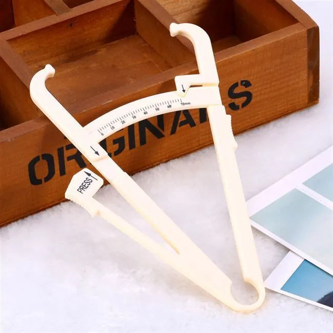 White acrylic body fat caliper skin fold thickness measuring tool on grey background.