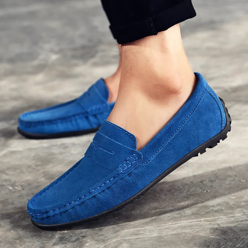 Men's brown suede casual loafers with a round toe, flat rubber sole, and visible stitching on a white background.