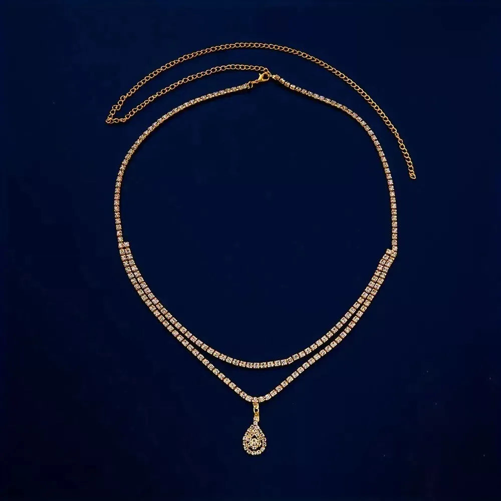 Gold and silver waist chain with a water drop pendant and rhinestone details on a model.