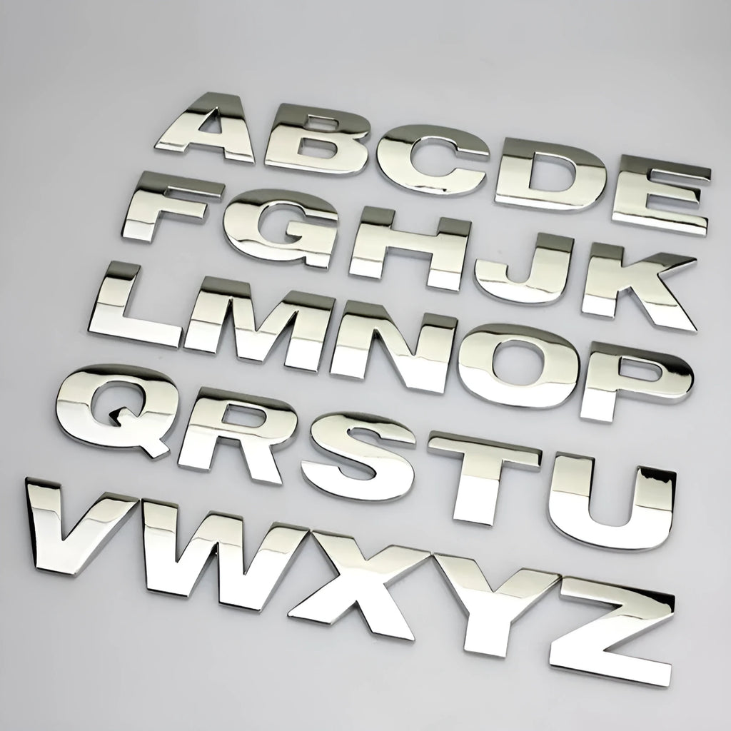 3D metal car letter sticker in zinc alloy, shown in black and silver finishes, approx. 2.5 cm in size.