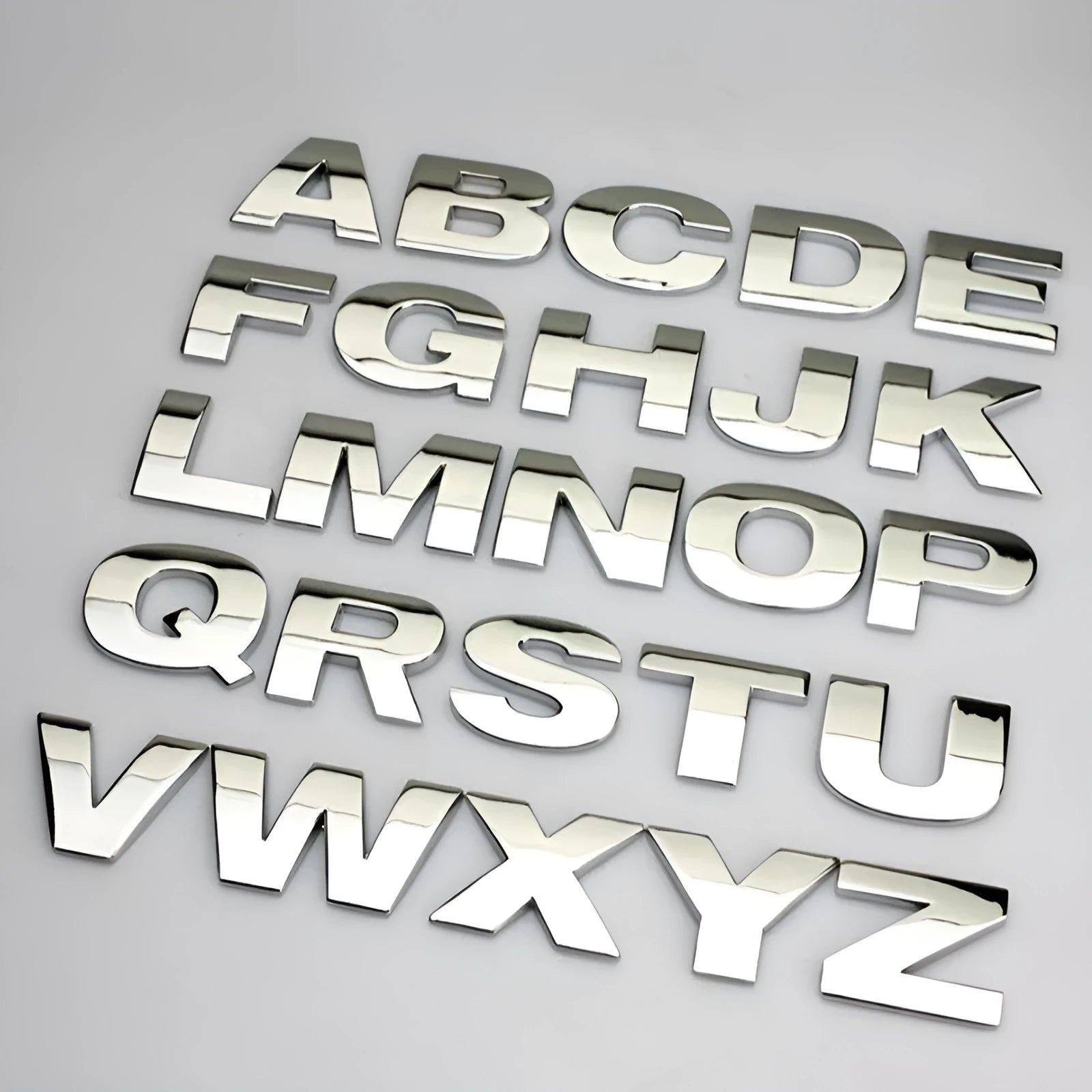 3D metal car letter sticker in zinc alloy, shown in black and silver finishes, approx. 2.5 cm in size.
