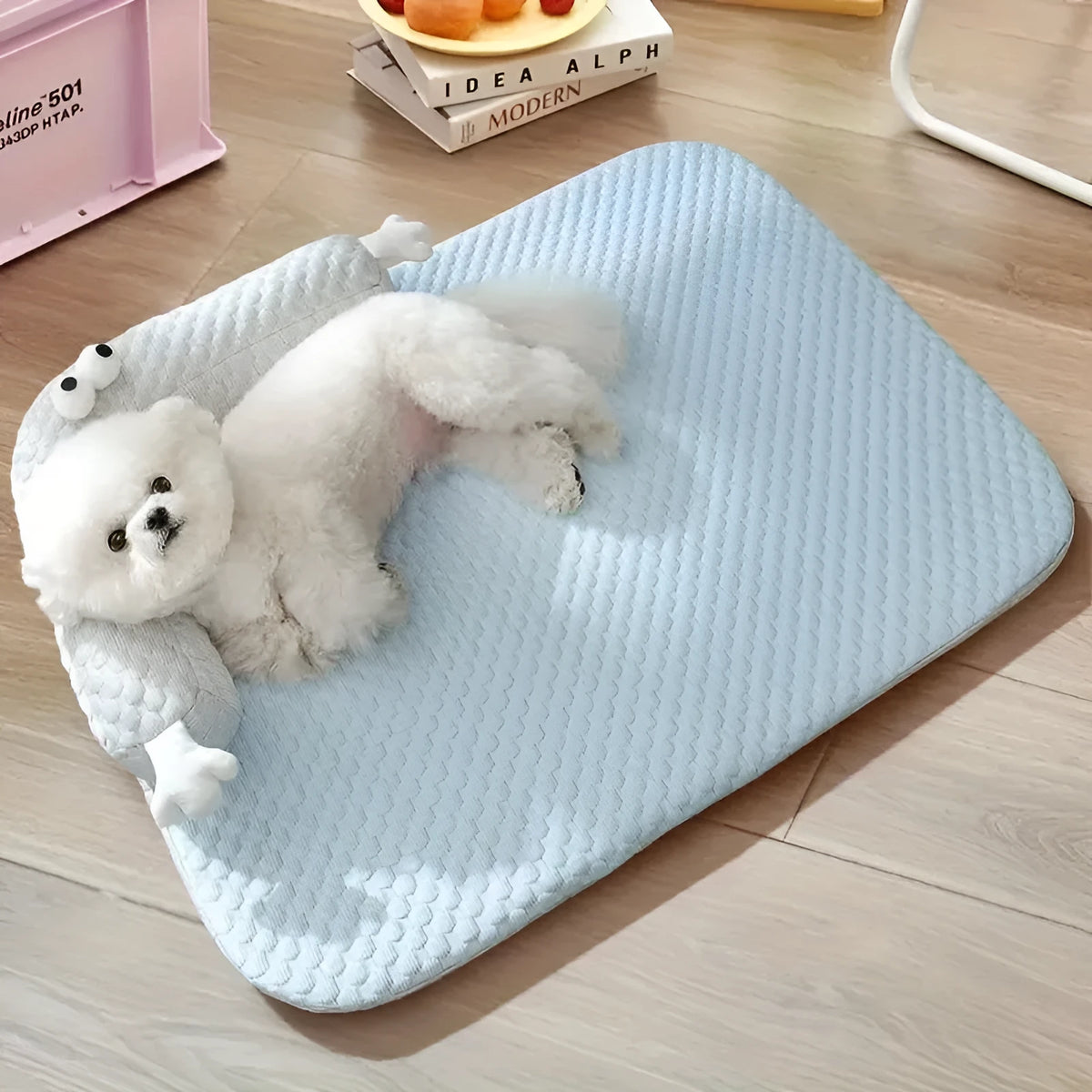 Blue and yellow pet bed cushion with big-eyed monster design on a non-slip base for dogs and cats.