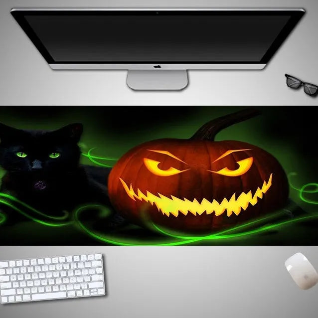 Oversized rectangular Halloween-themed mouse pad on a desk, showing one of 28 graphic designs.